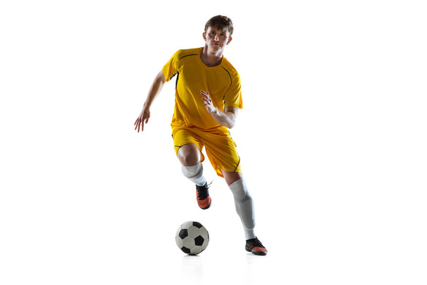 Jeune homme, joueur de football masculin s'entraînant isolé sur fond blanc. - Photo, image