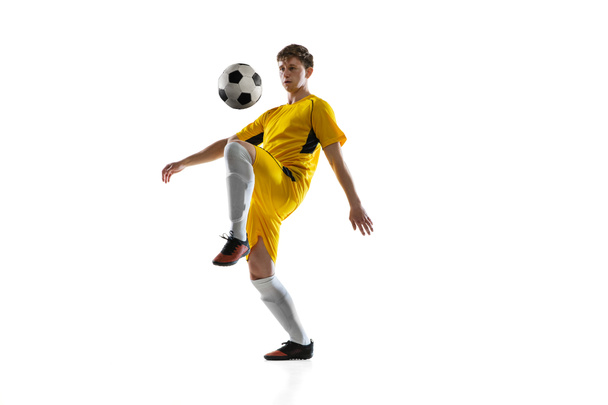 Jongeman, mannelijke voetbal speler training geïsoleerd op witte achtergrond. - Foto, afbeelding
