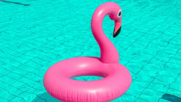 Letní zábava izolovaná. Růžové nafukovací plameňák v bazénu vody pro letní pláž pozadí. Vtipná ptačí hračka pro děti - Fotografie, Obrázek