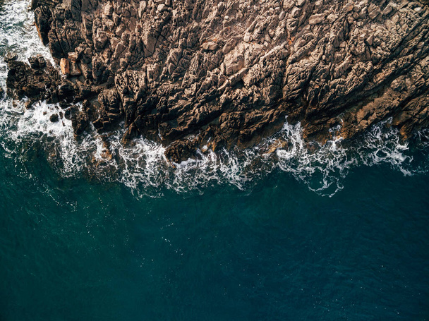Top view of the blue sea with waves beating on beach and rocks. - Foto, afbeelding
