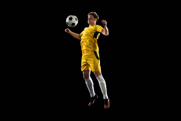 Young man, male soccer football player training isolated on black background. - Photo, Image