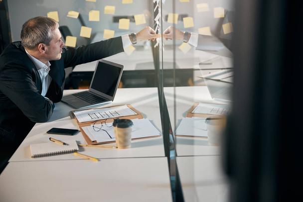 Businessman using sticky notes in modern office - Photo, Image
