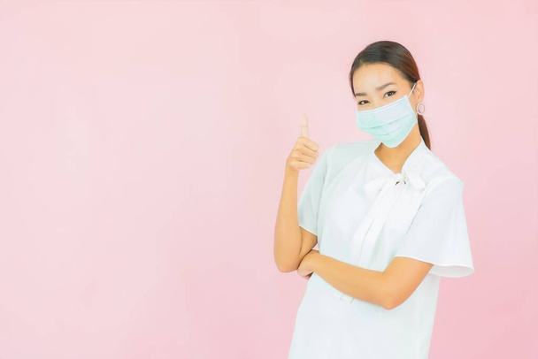 Retrato hermosa joven mujer asiática usar máscara para proteger covid19 sobre fondo rosa - Foto, Imagen