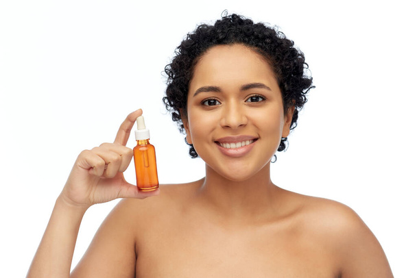 happy african american woman with bottle of serum - Zdjęcie, obraz
