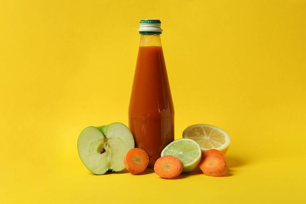 Bottle of juice and ingredients on yellow background - Foto, imagen