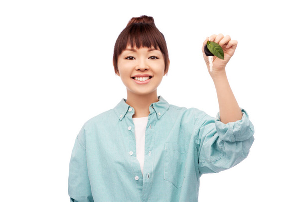 mujer asiática feliz sosteniendo la llave del coche con hoja verde - Foto, Imagen