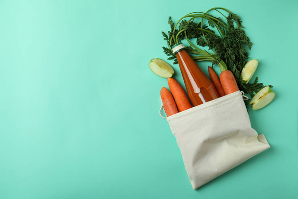 Bag with bottle of apple - carrot juice and ingredients on mint background - Fotografie, Obrázek