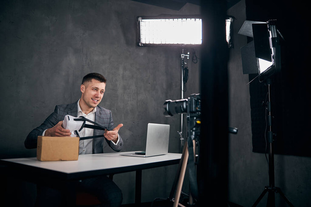 Gioioso giovane uomo registrazione unboxing video in studio - Foto, immagini