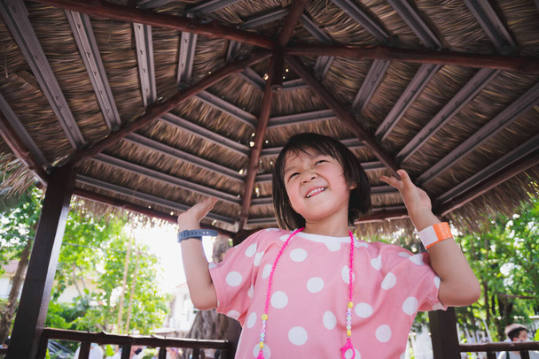 Egy 5 éves lány táncol egy természetes levelekkel borított pavilonban. A fiatal srác csinos arcot vágott. Egy rózsaszín pöttyös ruhát viselő gyerek boldog. Édes mosoly. Nyáron vagy tavasszal. - Fotó, kép