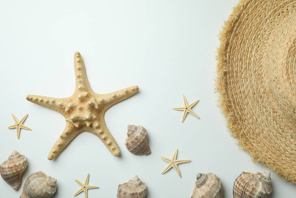 Sombrero de paja y conchas marinas sobre fondo blanco - Foto, imagen
