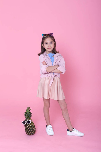 Summer fashion concept. cheerful little girl in big pineapple sunglasses on pink background. - Φωτογραφία, εικόνα