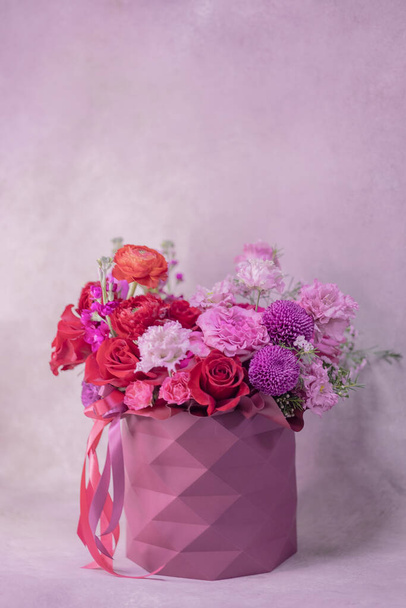Cylindrical geometric pattern box vase with lush bouquet of red, light pink, purple, white cute delicate small roses of different sizes, flowers. Place for text - Photo, image