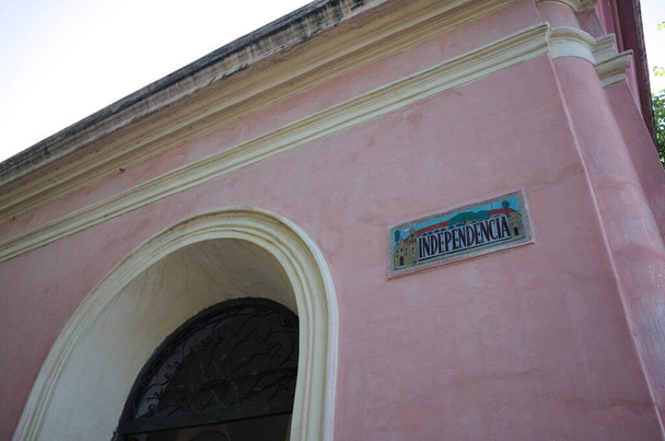 Placa de mosaico com inscrição Independencia que significa independência em espanhol no fundo da parede rosa de um edifício antigo com arco amarelo na área histórica da cidade de Córdoba, na Argentina - Foto, Imagem