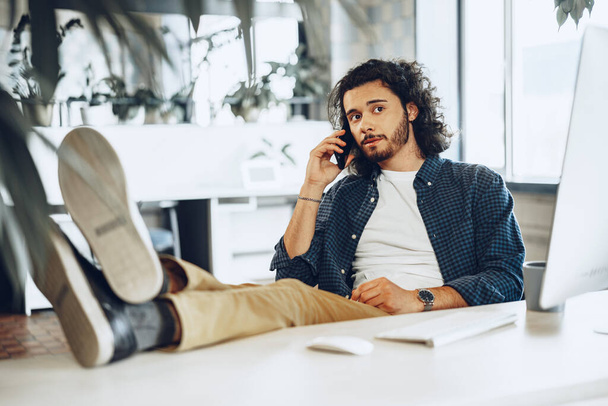 Casually dressed young businessman using mobile phone in office - Foto, Imagen