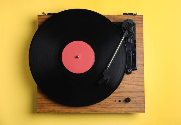 Modern vinyl record player with disc on yellow background, top view - Fotografie, Obrázek