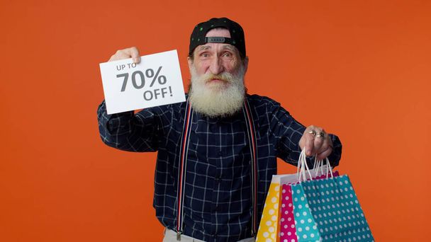 Пожилой бородатый мужчина показывает сумки и до 70 процентов от надписей текст, Черная пятница - Фото, изображение