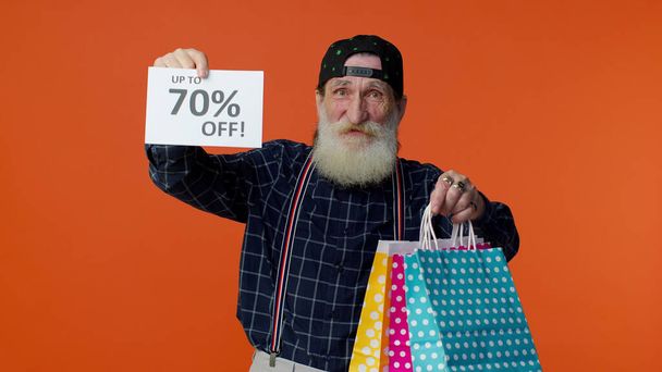 Yaşlı sakallı adam alışveriş torbalarını gösteriyor ve% 70 'e varan indirimli yazı pankartı, Kara Cuma - Fotoğraf, Görsel