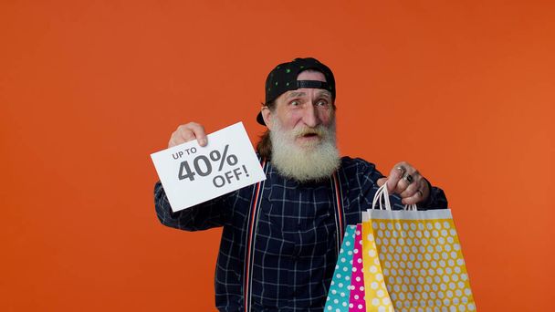 Hombre barbudo mayor mostrando bolsas de compras y hasta 40 por ciento de inscripciones banner, Viernes Negro - Foto, imagen