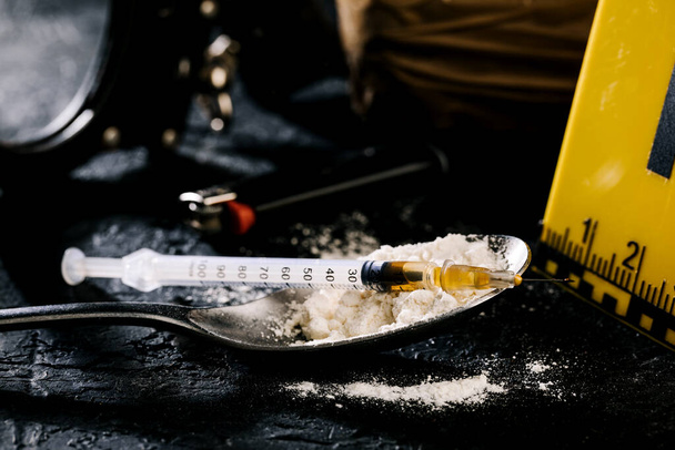 Heroína en una jeringa y polvo de heroína sobre un fondo negro. el concepto de sustancia narcótica. - Foto, imagen