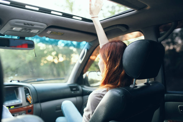 mujer con una ventana abierta en el asiento delantero de un coche gesto con las manos salón interior compañero de viaje - Foto, imagen