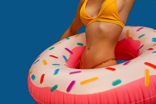 jong vrouw meisje poseren met donut-vormige zwemmen opblaasbare ring geïsoleerd op blauwe achtergrond. - Foto, afbeelding