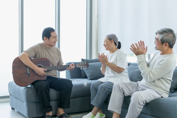 Alte Männer und Frauen hören im Wohnzimmer Musik mit Gitarre. Seniorentreff, Seniorentreff. - Foto, Bild