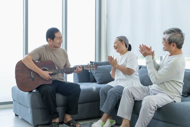 Alte Männer und Frauen singen im Wohnzimmer zur Musik mit der Gitarre. Seniorentreff, Seniorentreff. - Foto, Bild