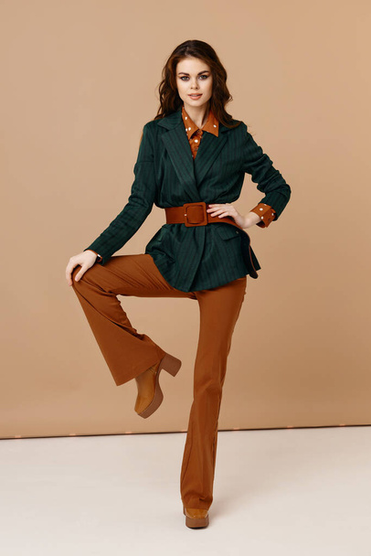charming brunette in a suit bent her leg at the knee beige background models - Φωτογραφία, εικόνα