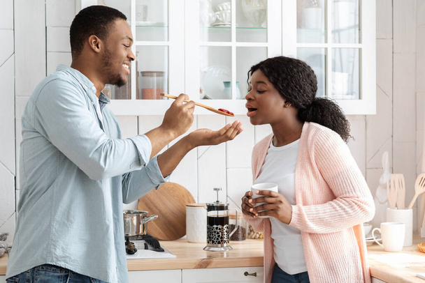 Romantic african american couple cooking healthy food together in kitchen - 写真・画像