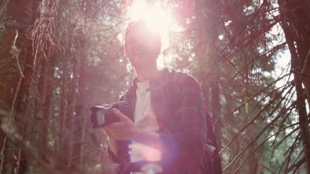 Egy férfi, aki tájképeket készít a kamera előtt. Fényképezőgépet használó utazó az erdőben - Felvétel, videó