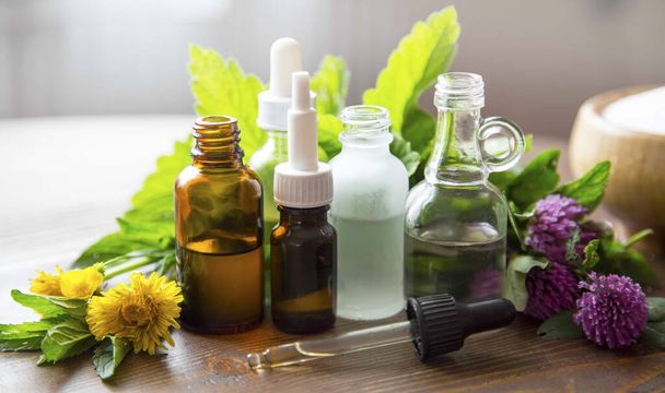Альтернативная медицина, лечебные травяные масла, растительные ароматические масла с лекарственными растениями и травами, бутылки эфирных масел - Фото, изображение