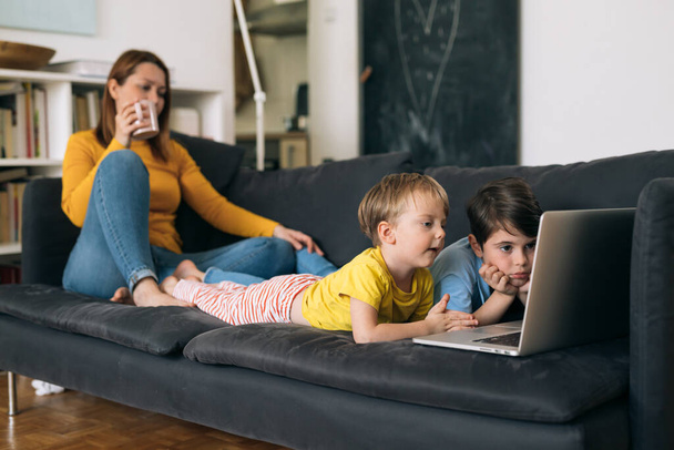 mother with her two kids spending time at home. kids watching computer - Фото, зображення