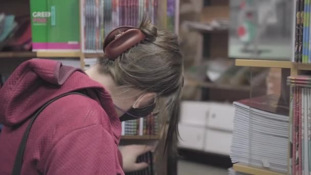 ウイルスに対する眼鏡やマスクを身に着けている女性は、新しい学校の年のためのノートを購入 - 映像、動画