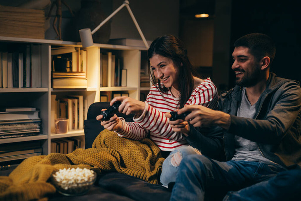 young couple playing video games at home. evening scene - Фото, зображення