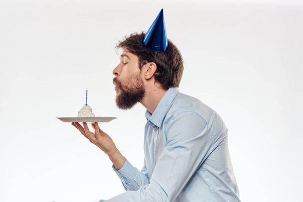a man with a beard holds a cake in his hand on a light background birthday - Photo, Image