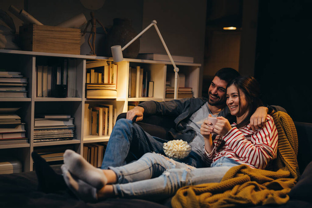 young couple watching television together at home - Fotoğraf, Görsel
