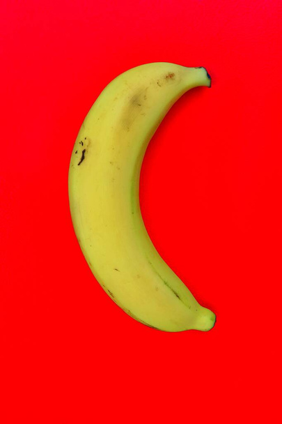 Yellow banana tropical fruit on red background or texture - Foto, imagen