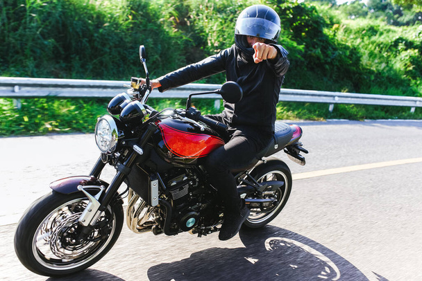 Motorkář jezdí na své motorce a ukazuje na kameru - Fotografie, Obrázek