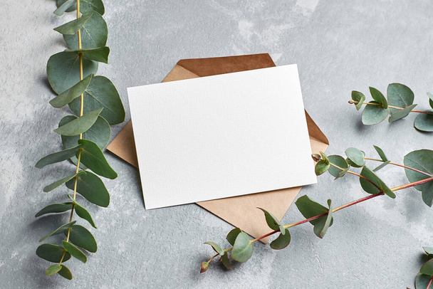 Greeting card with copy space, envelope and eucalyptus twigs on grey concrete background, wedding invitation - Foto, imagen
