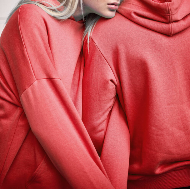 Γυναίκα και άντρας στέκονται με κόκκινες μπλούζες. Βουργουνδία κουκούλα για το μοντέλο - Φωτογραφία, εικόνα