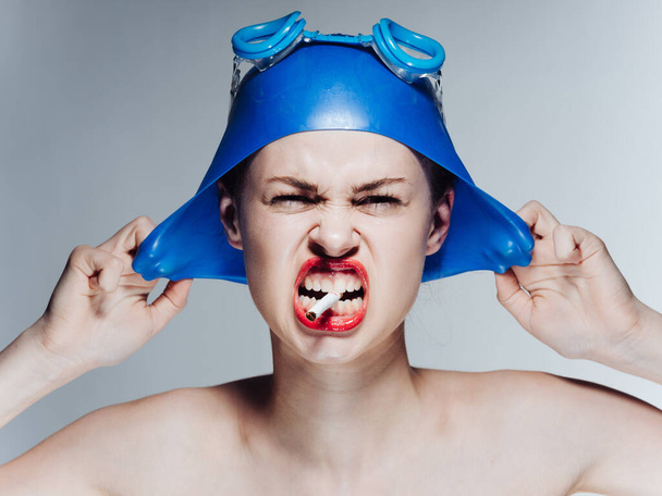 Woman swimmer in a blue swimming cap and glasses with a cigarette in her teeth - Foto, Imagen