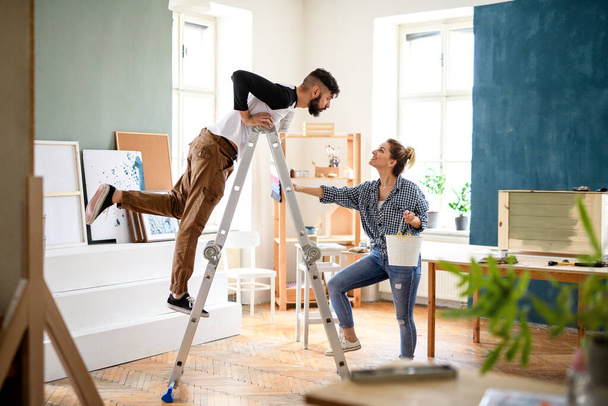 Mid adults couple having fun when painting indoors at home, relocation and diy concept. - Foto, Imagem