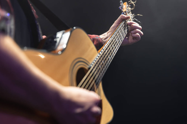Κλασική ακουστική κιθάρα στα χέρια ενός μουσικού αντιγράφου χώρου. - Φωτογραφία, εικόνα