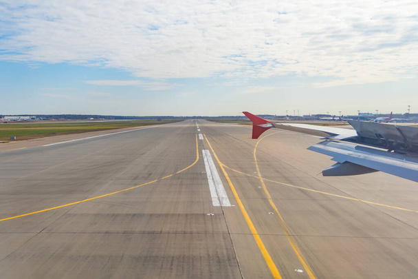 Jet plane window sky view with machine wing between landing runway road in airport - Zdjęcie, obraz