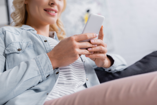 Cropped view of smartphone in hands of smiling woman on blurred background  - Photo, Image