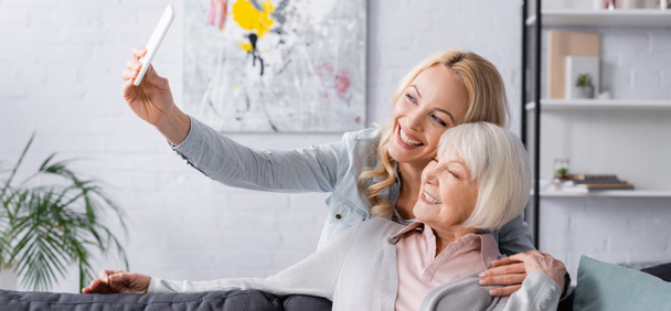 Smiling senior woman taking selfie near daughter, banner  - Photo, image