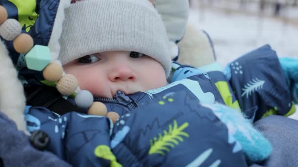 Κοντινό πλάνο, ένα μικρό παιδί κάθεται σε ένα καρότσι το χειμώνα - Πλάνα, βίντεο