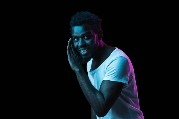 Mladý afroameričan izolovaný na tmavém pozadí v neonovém světle - Fotografie, Obrázek