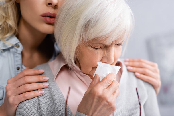 Senior woman with napkin crying near daughter  - Photo, Image