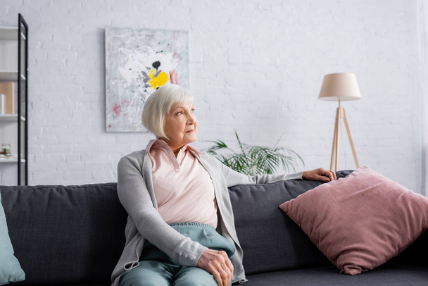 Grey haired woman looking away in living room  - Fotó, kép